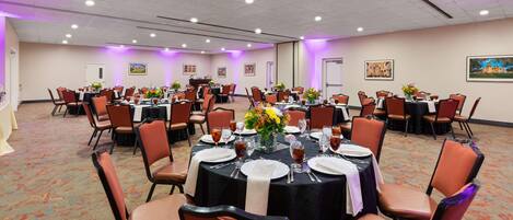 A conference room with round tables, orange chairs, and purple lighting.
