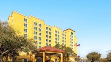 A yellow hotel with a red roof, multiple windows, and a flag.