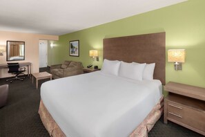 A hotel room with a large bed, a desk, a chair, a sofa, and a nightstand with lamps. - La Quinta Inn & Suites by Wyndham San Antonio Medical Ctr NW (San Antonio)