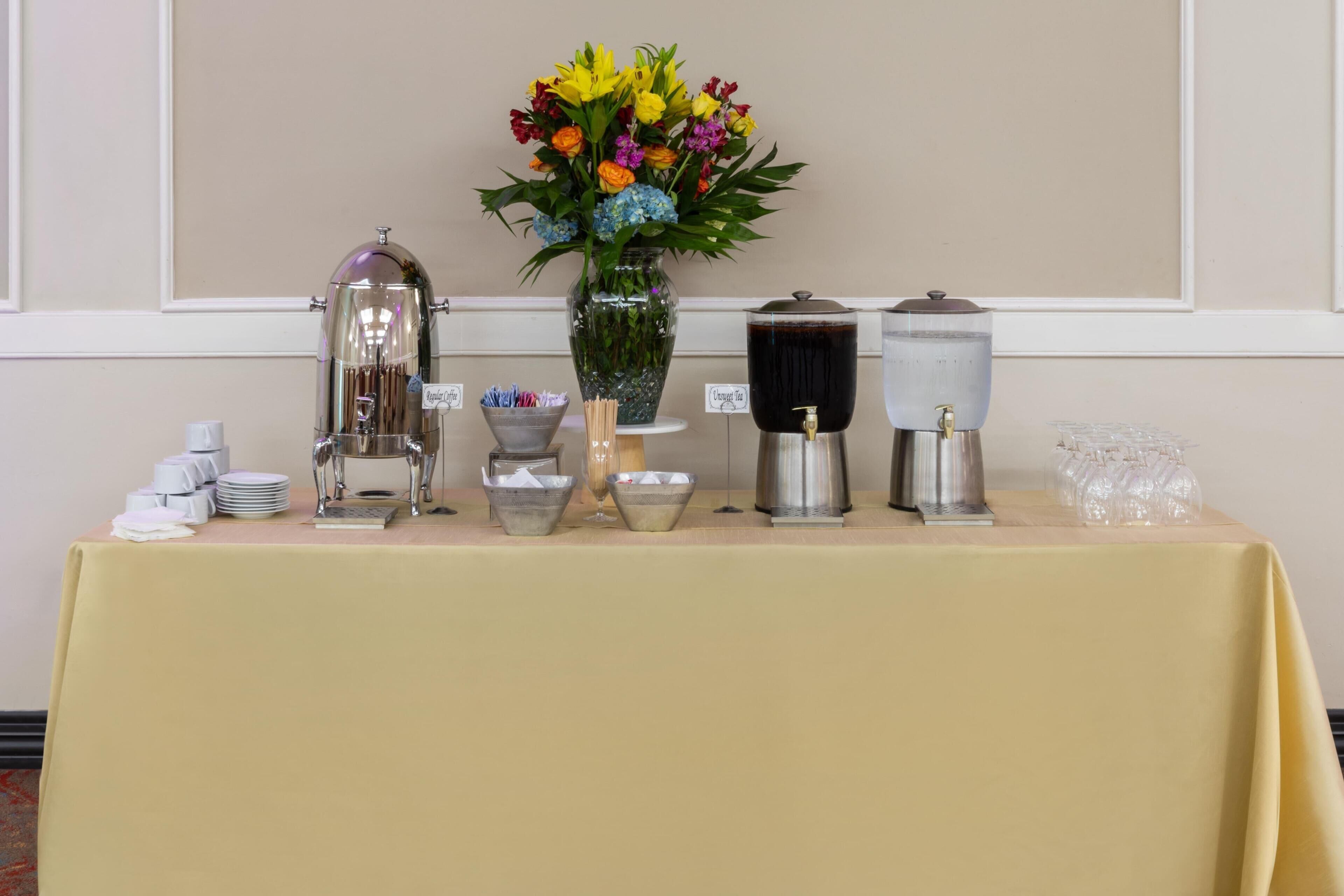 Een buffet met een koffiehoek, een bloemenvaas en diverse opschepkommen.