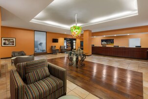 Un vestíbulo de hotel con mostrador de recepción, zona de estar y una araña.