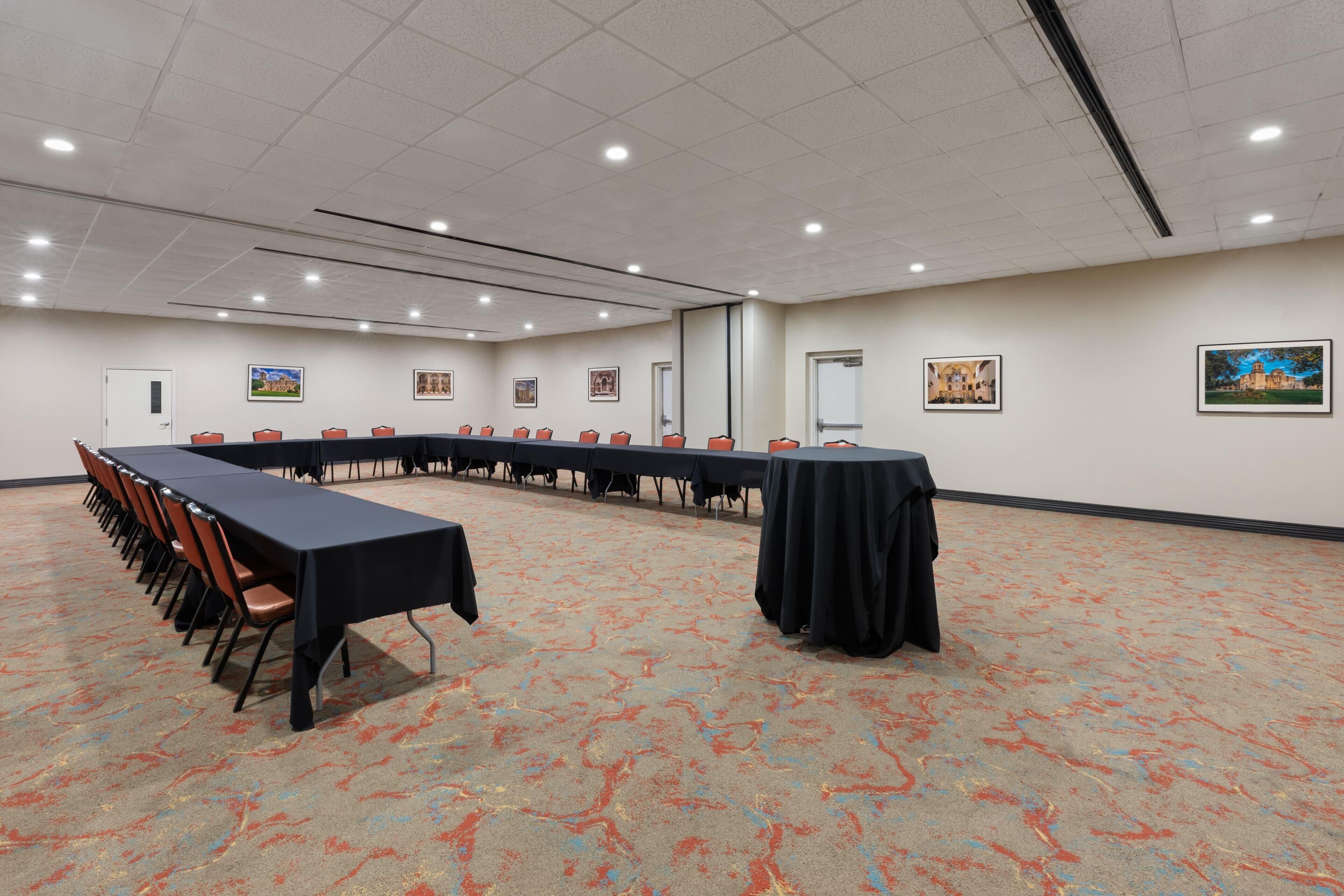 Una sala de conferencias con una larga mesa, sillas y piso alfombrado.