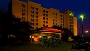 A hotel with a red-roofed entrance, multiple floors, and a visible flag.
