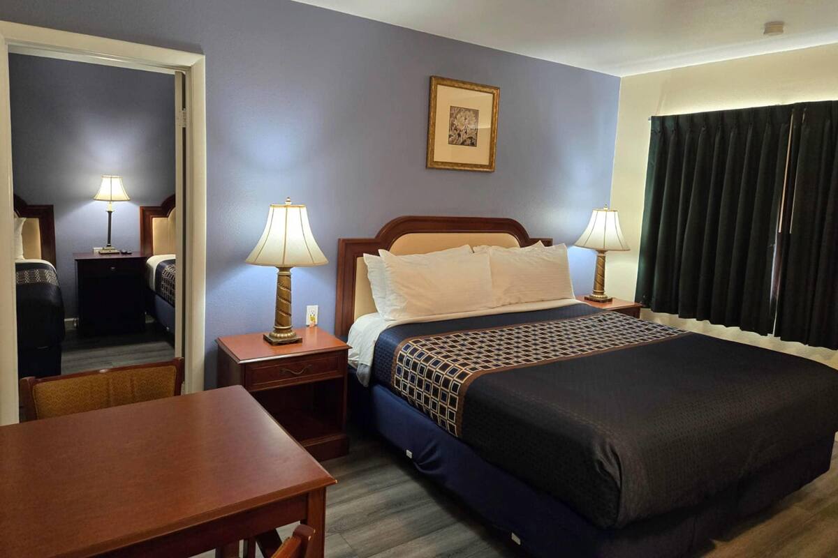 A hotel room with a bed, two bedside tables with lamps, a desk, and a chair.