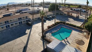 A hotel with a swimming pool, parking lot, and a view of mountains. - Rodeway Inn & Suites Blythe I-10 (Blythe)