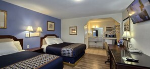 Ett hotellrum med två sängar, ett skrivbord, en spegel och en tv.