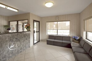 A reception area with a marble counter, a sofa, and a window with a view.