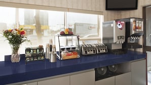 Un comptoir de cuisine avec un grille-pain, une machine à café et une fenêtre donnant sur un paysage urbain.