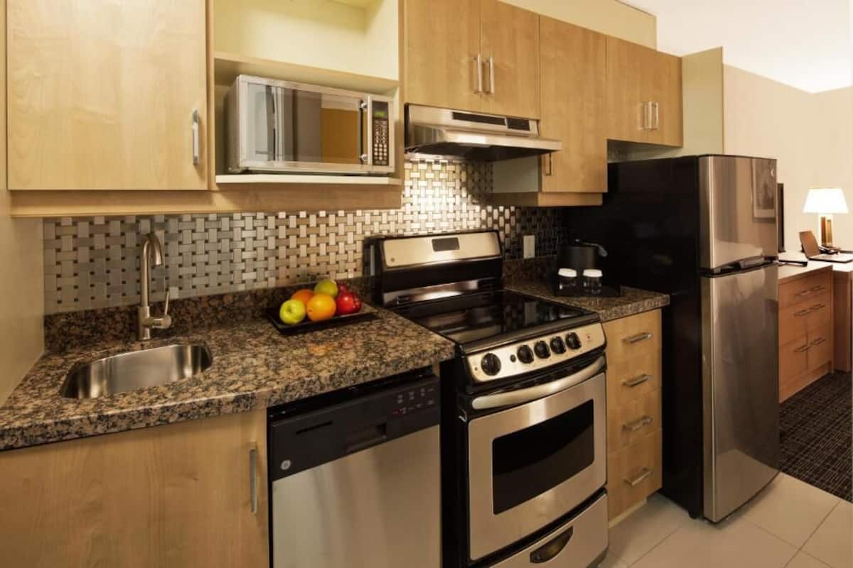 A kitchen with a microwave, stove, oven, refrigerator, and a sink.
