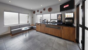 Un hall d’hôtel moderne doté d’un espace salon, d’un coin café et d’une grande fenêtre offrant une vue panoramique.