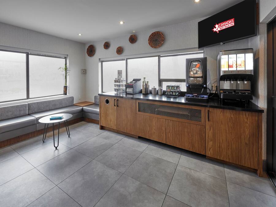 A modern hotel lobby with a seating area, a coffee station, and a large window offering a view.