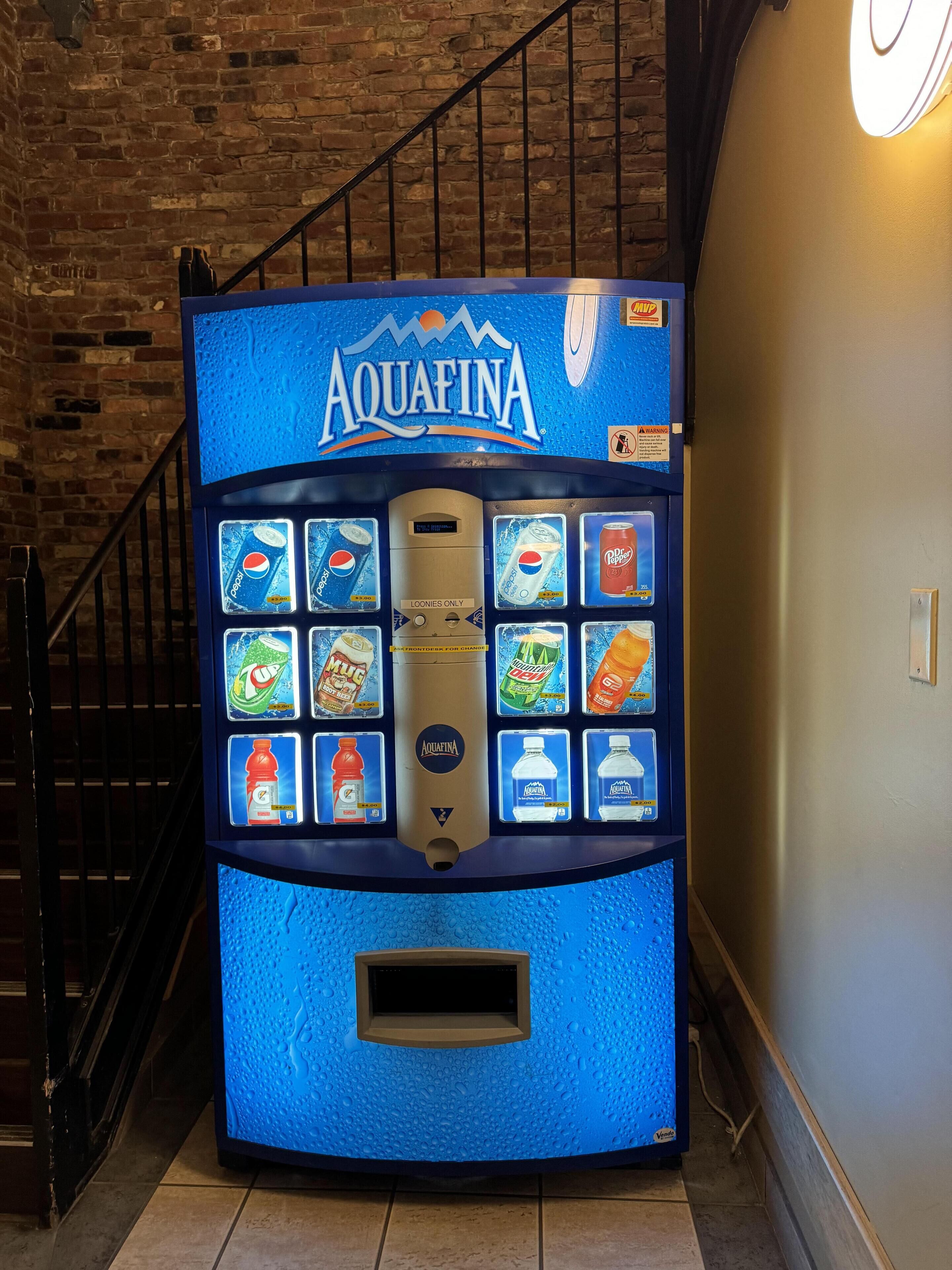 A vending machine with the Aquafina logo, offering various beverages including Pepsi, 7up, and Mountain Dew.