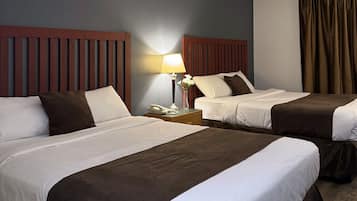 Une chambre d’hôtel avec deux lits, une table de chevet avec une lampe et une fenêtre avec des rideaux.