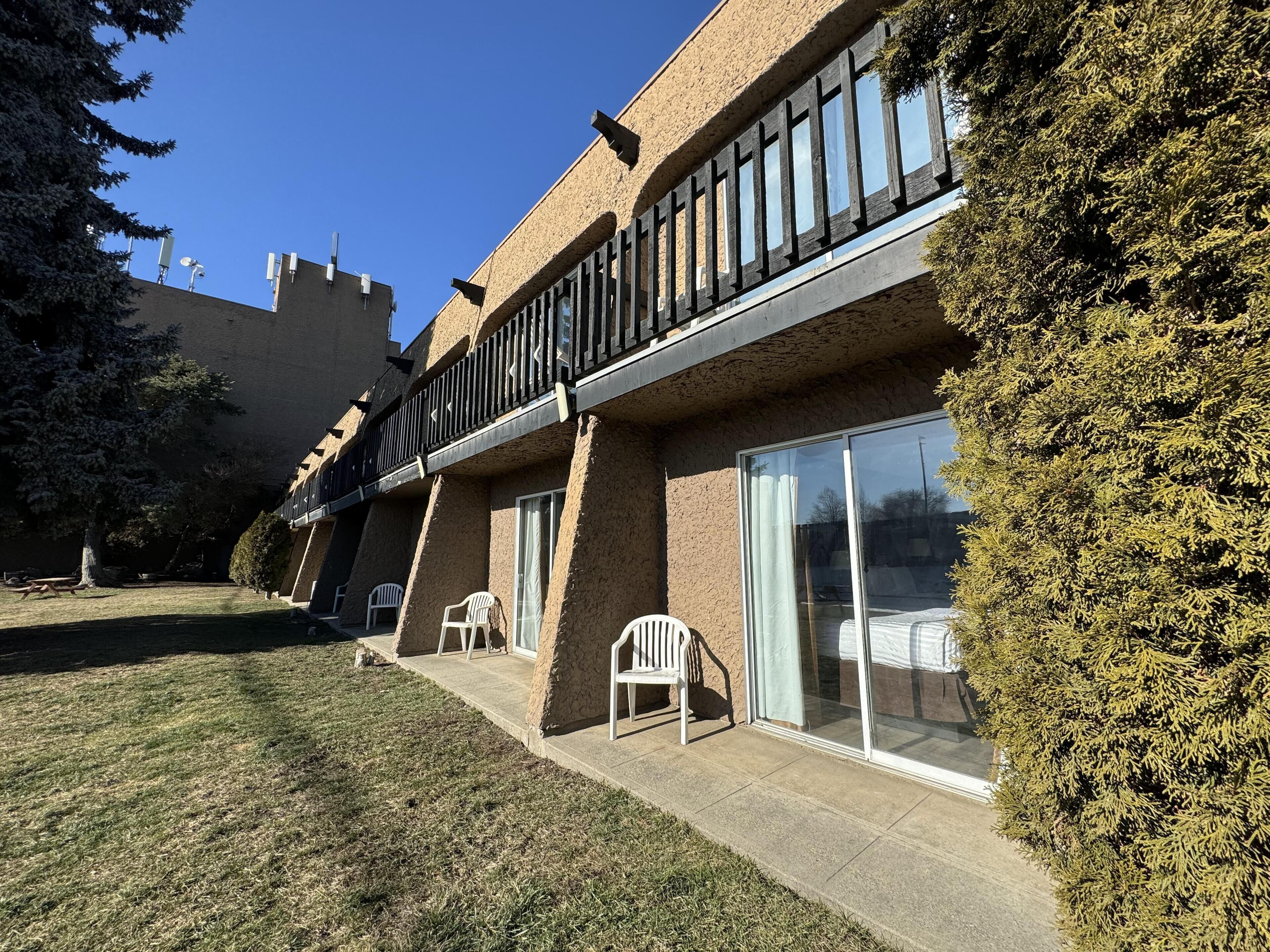 A building with a balcony, large windows, and a grassy courtyard.