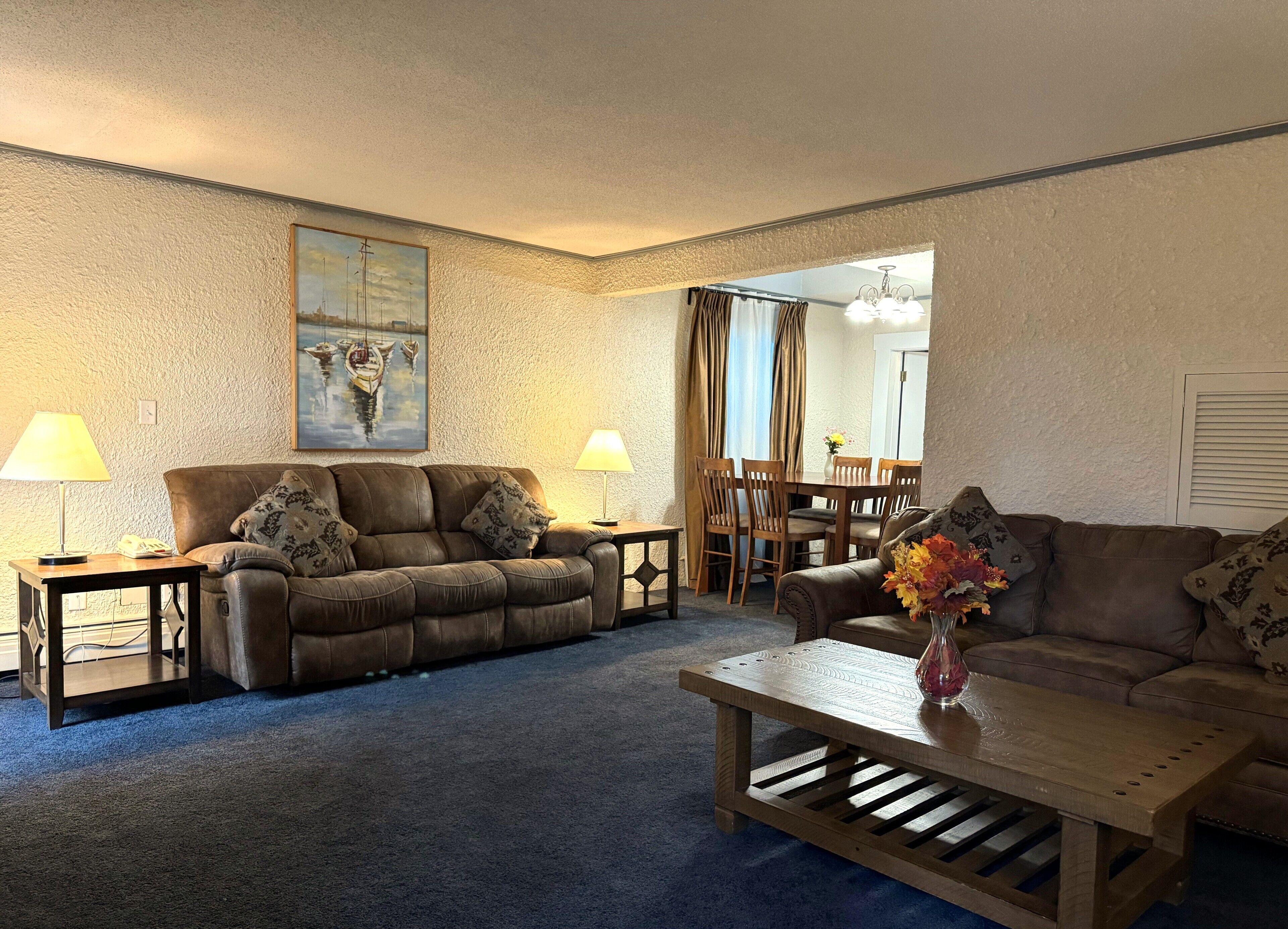 A living room with two sofas, a coffee table, and a dining area with a table and chairs.
