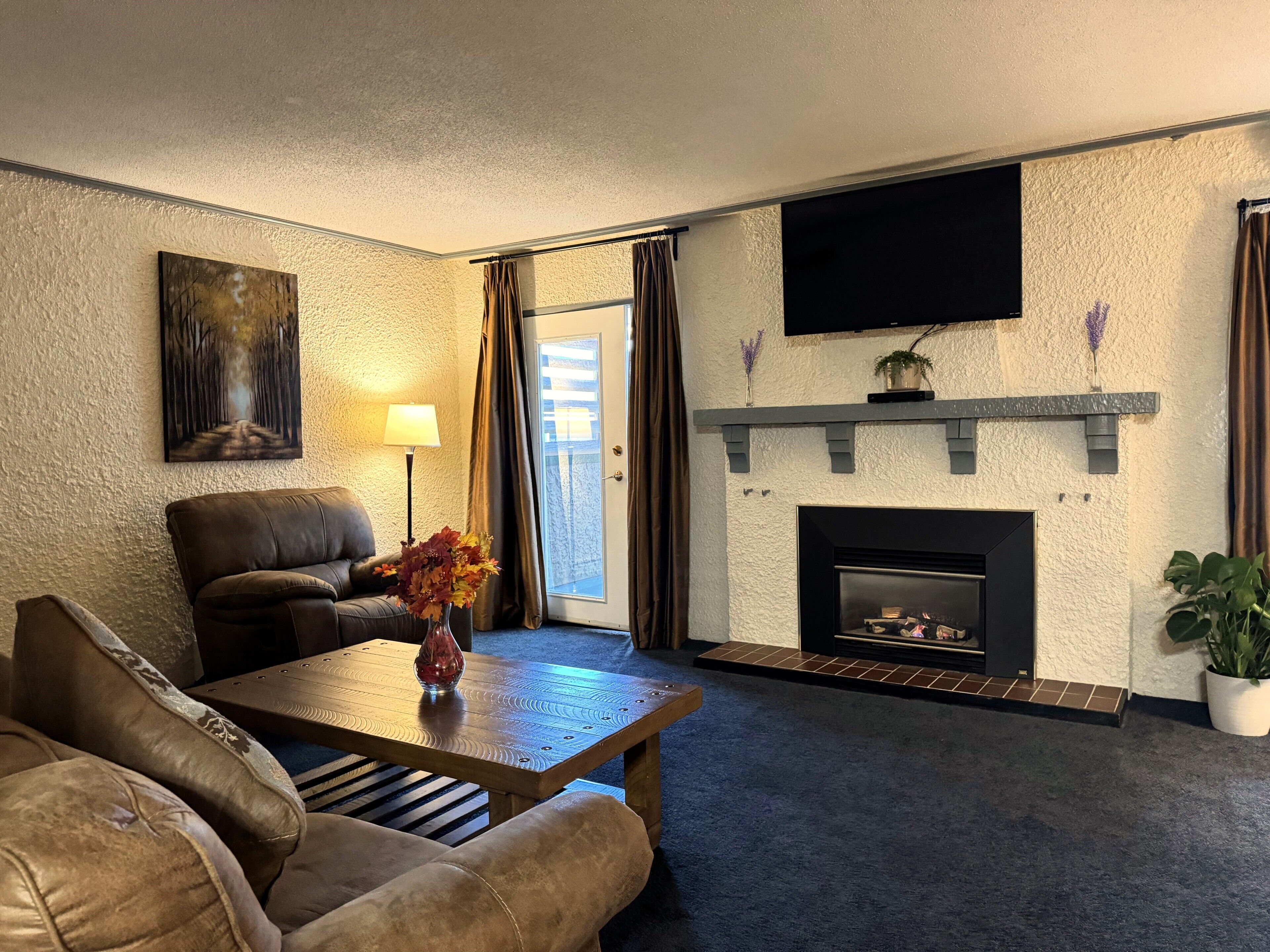 A living room with a fireplace, a sofa, a coffee table, and a television mounted on the wall.