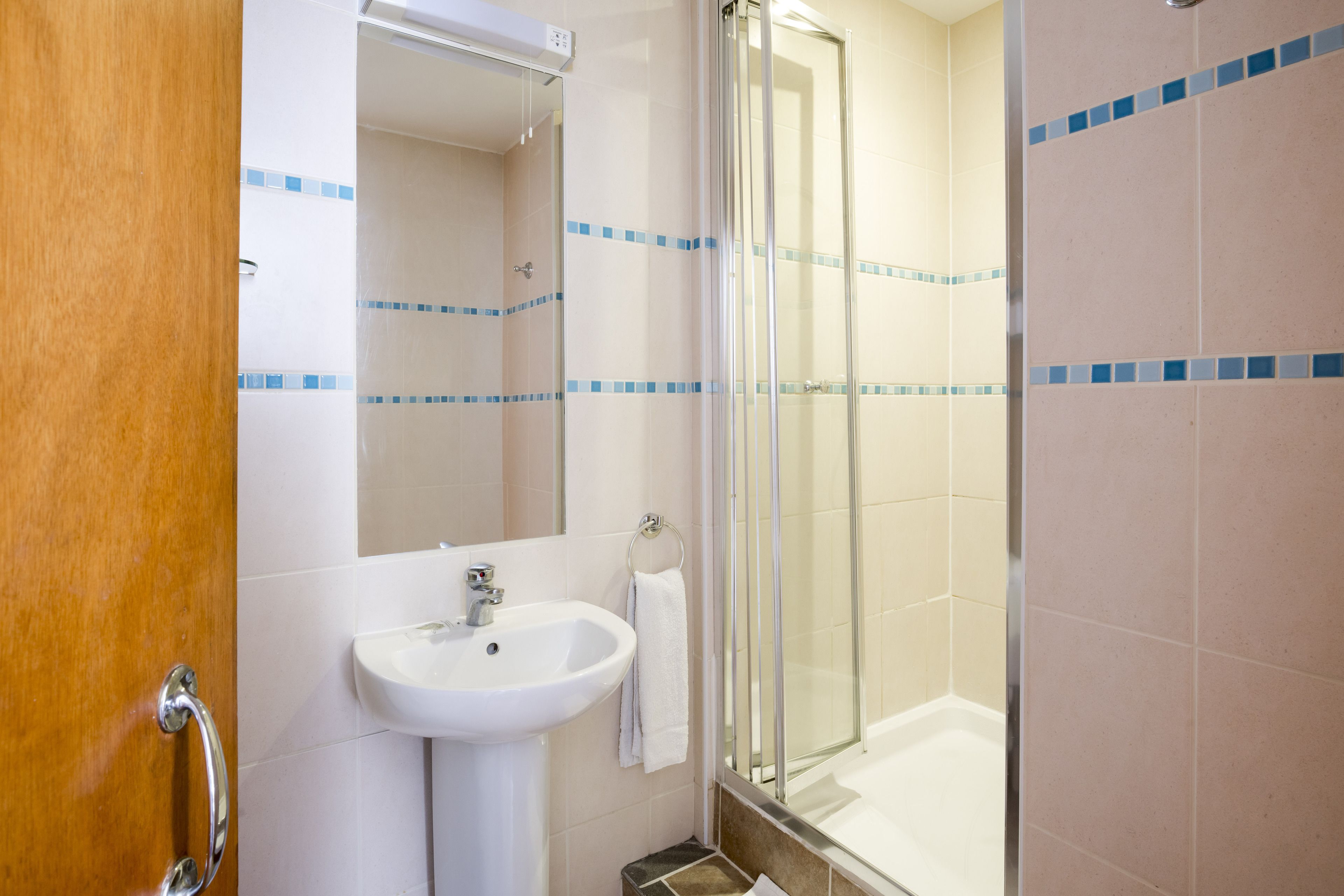 A bathroom with a sink, mirror, and shower.