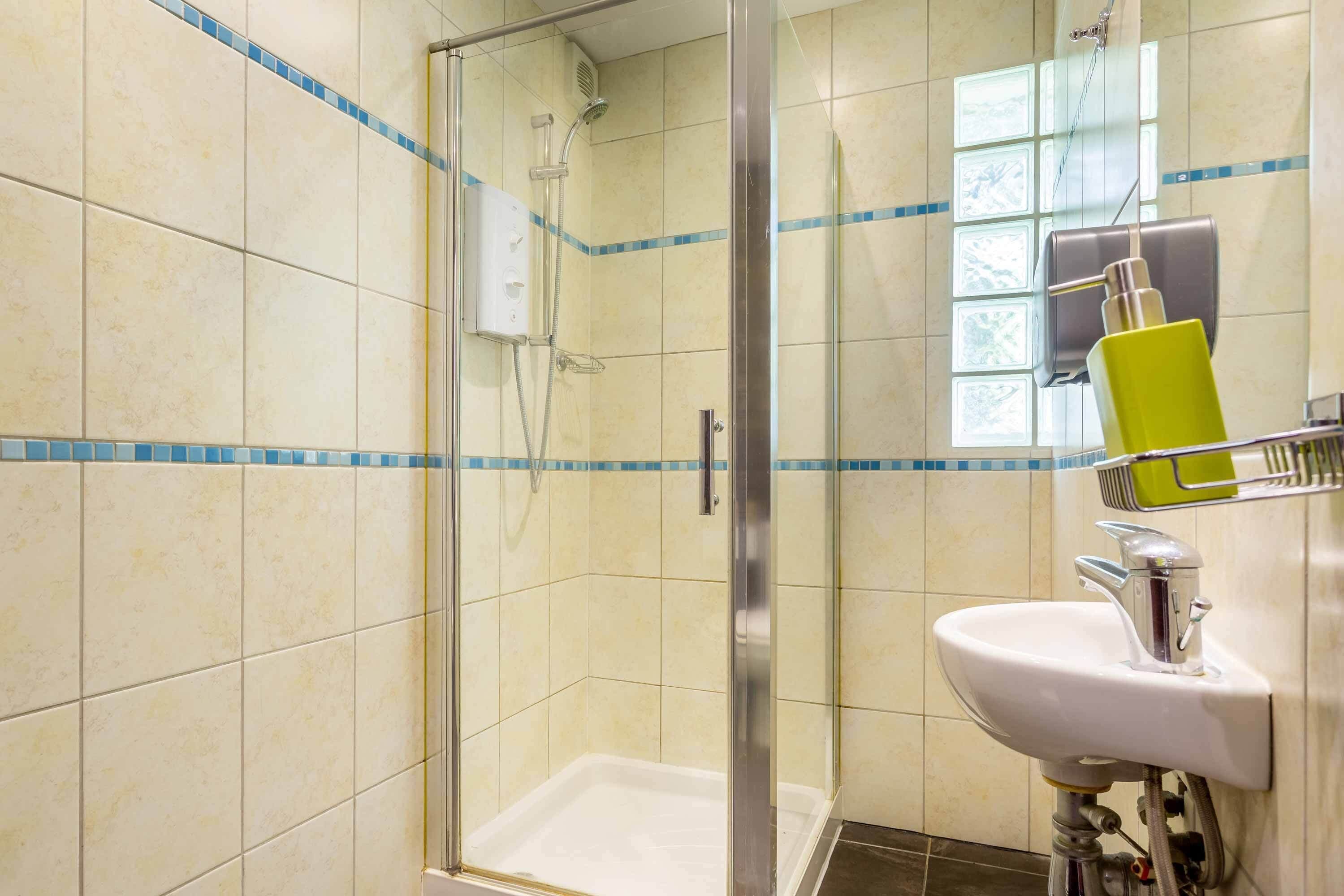 A bathroom with a glass-enclosed shower, a white sink, and a mirror.