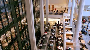 A multi-level atrium with numerous tables and chairs, surrounded by tall bookshelves. - St Athans Hotel (London)