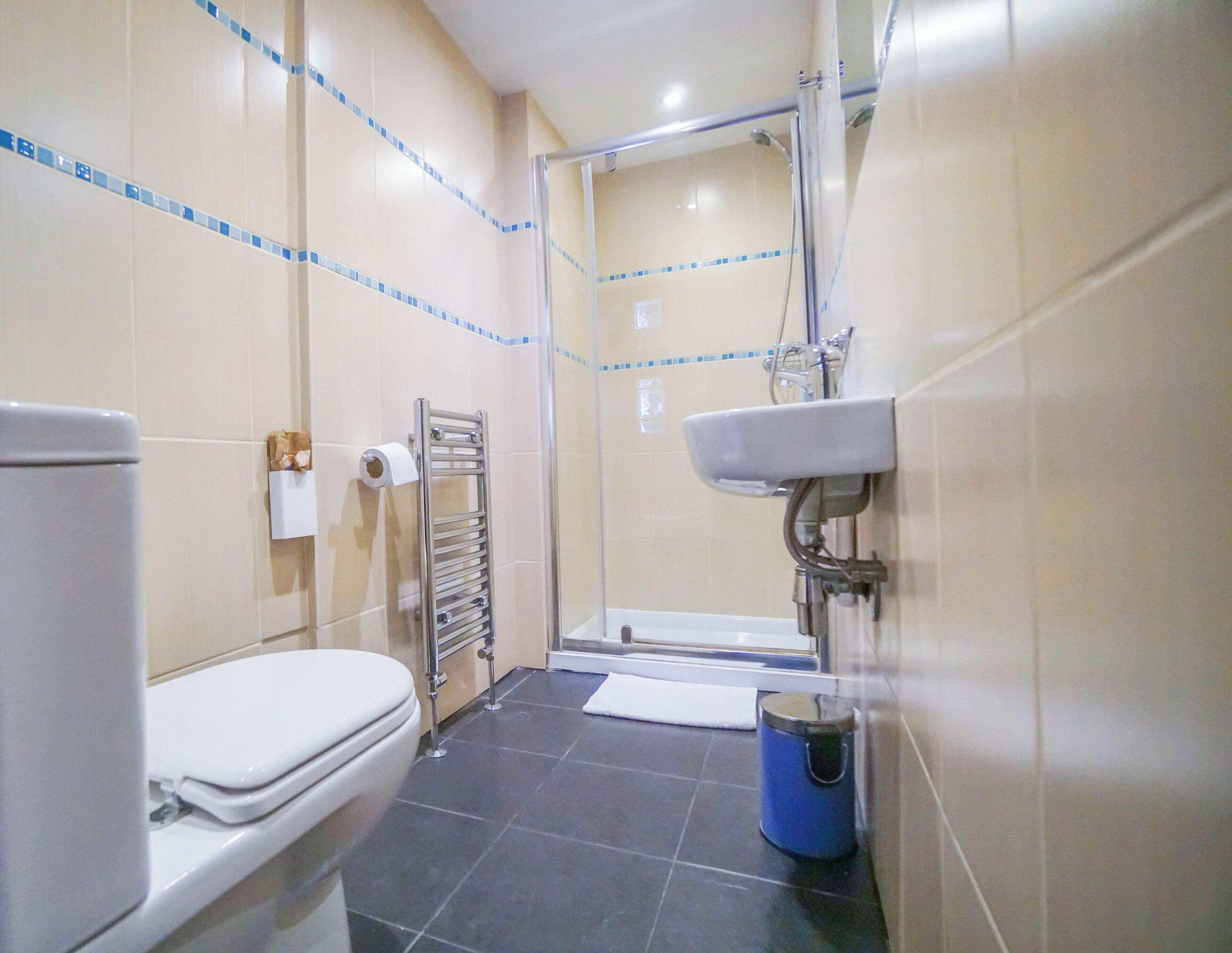 Un baño con inodoro, toallero, zona de ducha y lavamanos.
