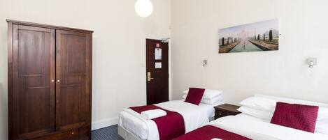 Una habitación de hotel con dos camas, un armario, una puerta con un letrero y un cuadro en la pared.