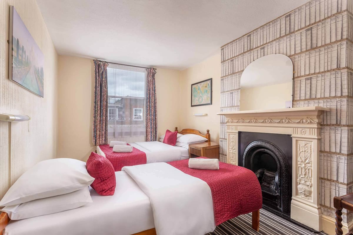 A hotel room with two beds, a fireplace, and a view of the city.