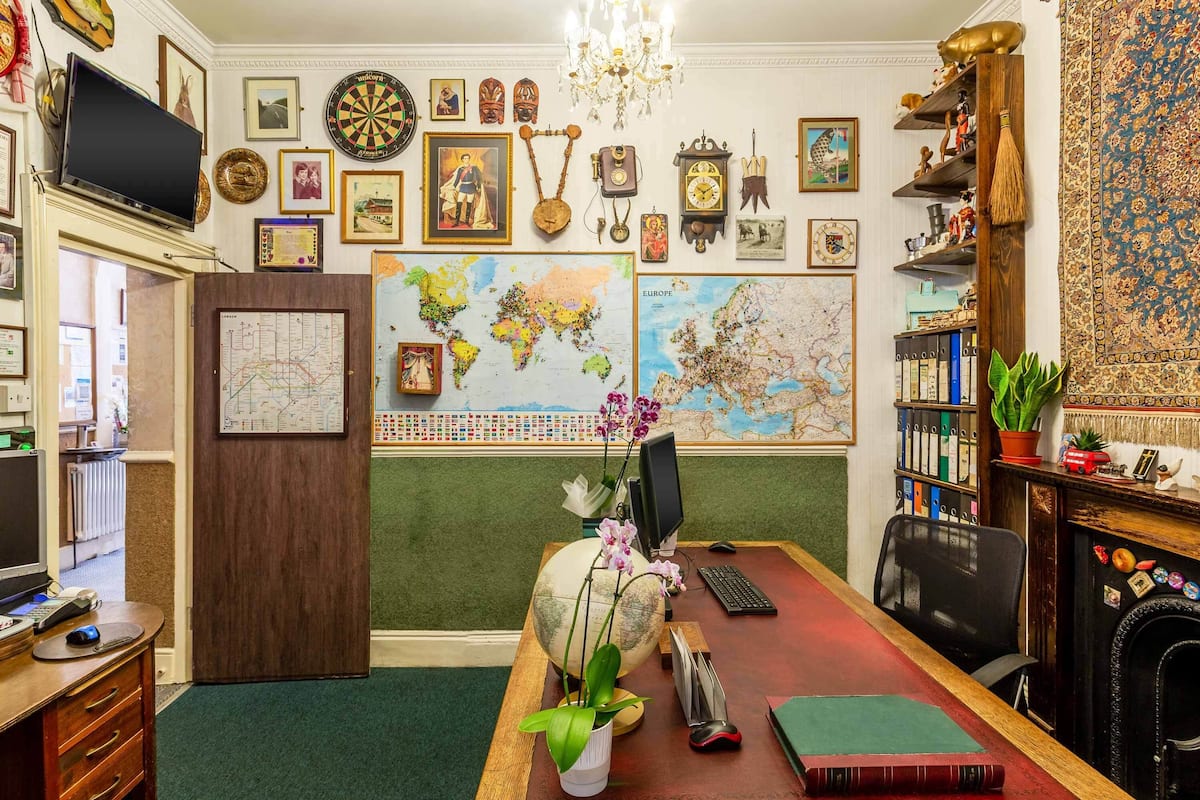 A room with a desk, computer, globe, maps, and various decorative items.