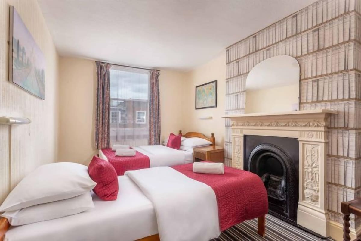 A hotel room with two beds, a fireplace, and a city view.