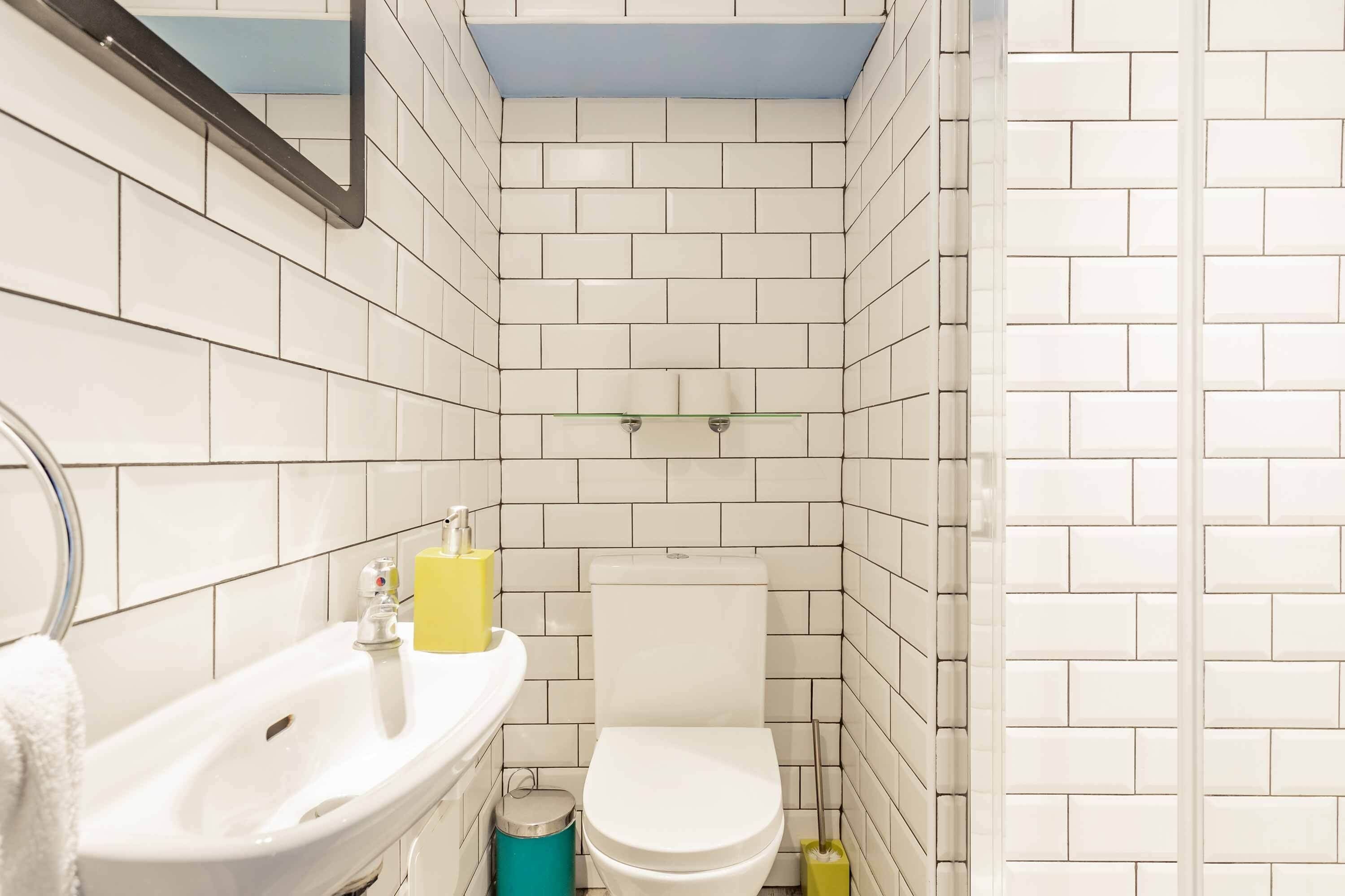Een kleine badkamer betegeld met een wastafel, toilet en spiegel.
