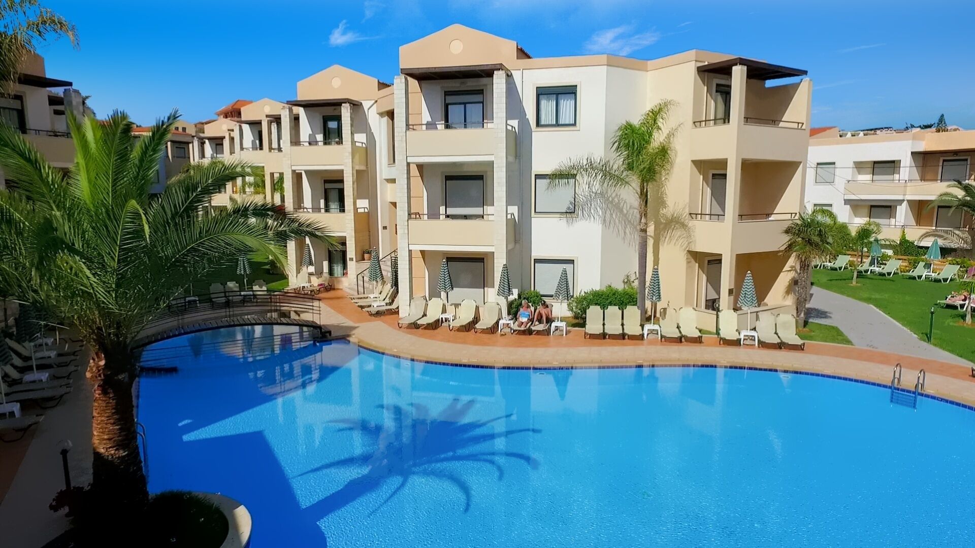 Um hotel moderno com piscina central, várias varandas e áreas de estar ao ar livre.