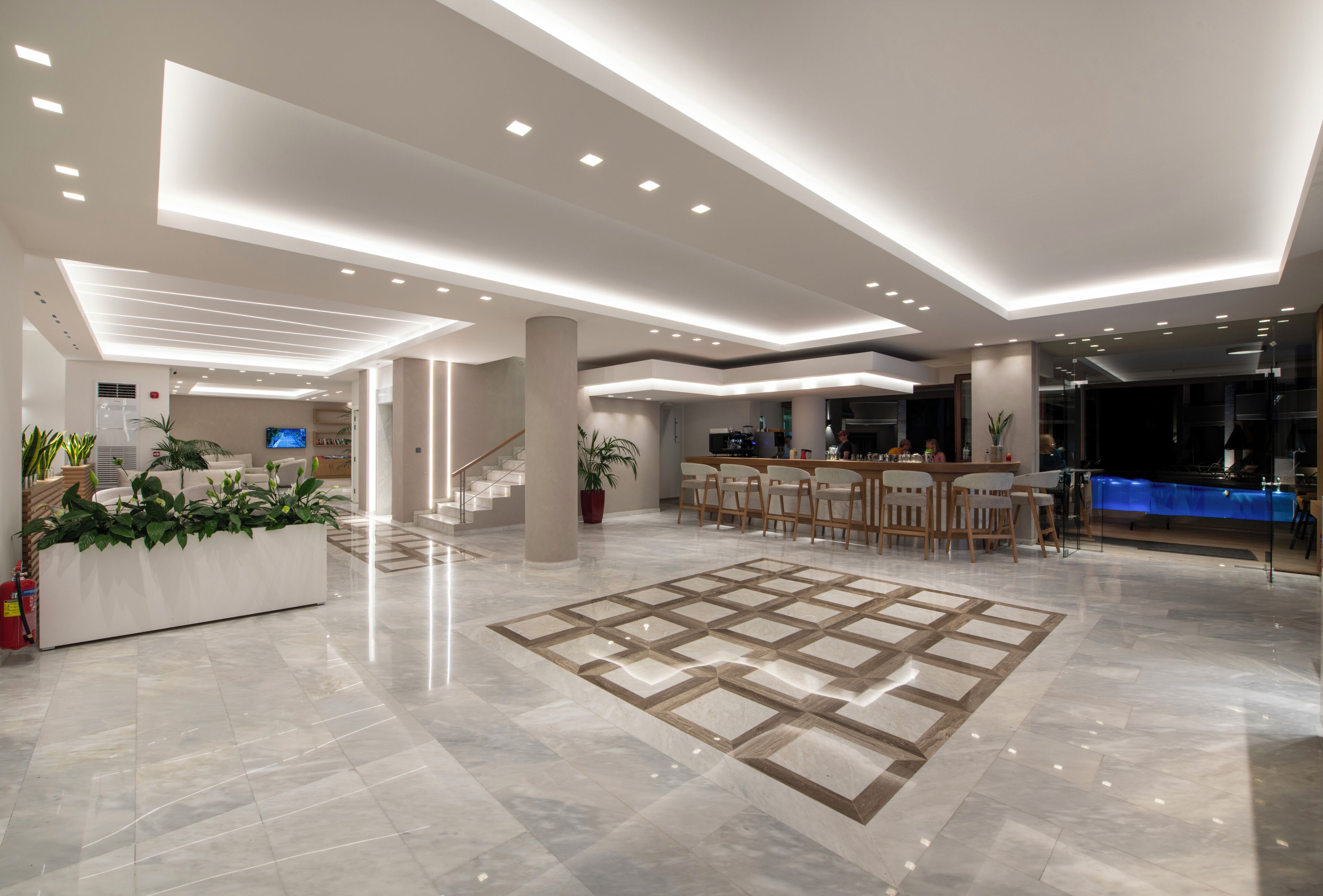 A spacious lobby with a central seating area, a reception desk, and a bar.