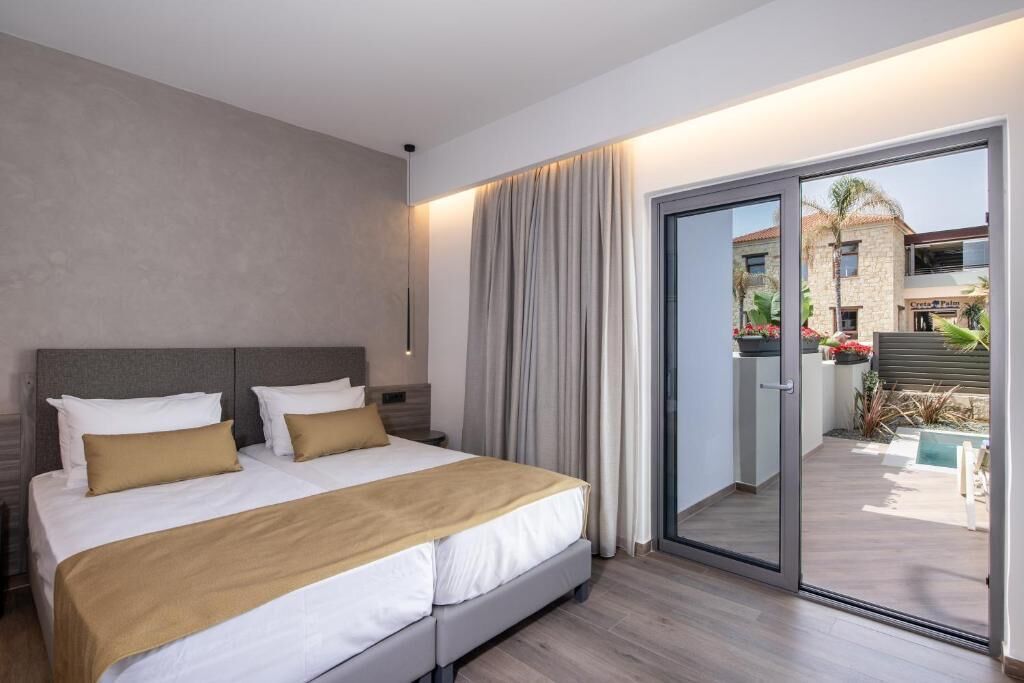A hotel room with a large bed, a sliding glass door to the outside, and a view of the building and pool.