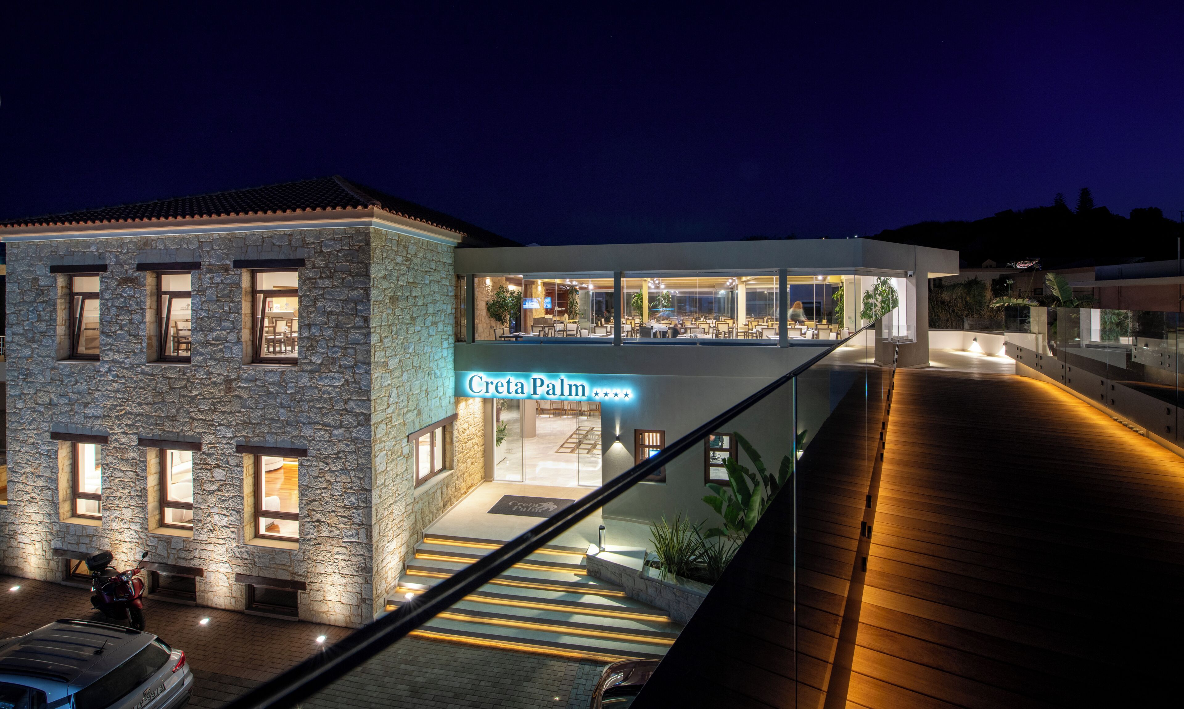 A hotel with a stone facade, a visible restaurant area, and a sign reading 'Creta Palm.'