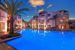 A modern hotel with a swimming pool, multiple balconies, and palm trees. - Creta Palm Hotel (Chania)