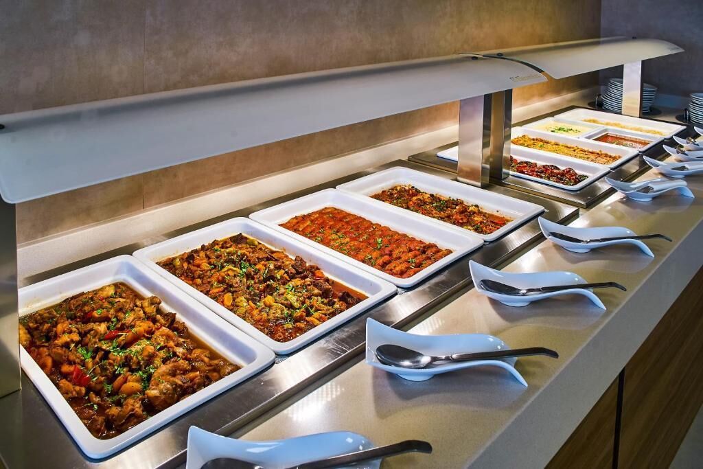A buffet with multiple food trays and serving utensils.