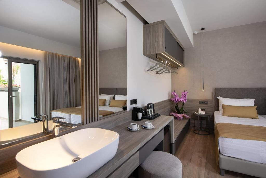Ein modernes Hotelzimmer mit einer großen Badewanne, einem Bett mit Kopfteil, einem Nachttisch mit Lampe und einem großen Spiegel.