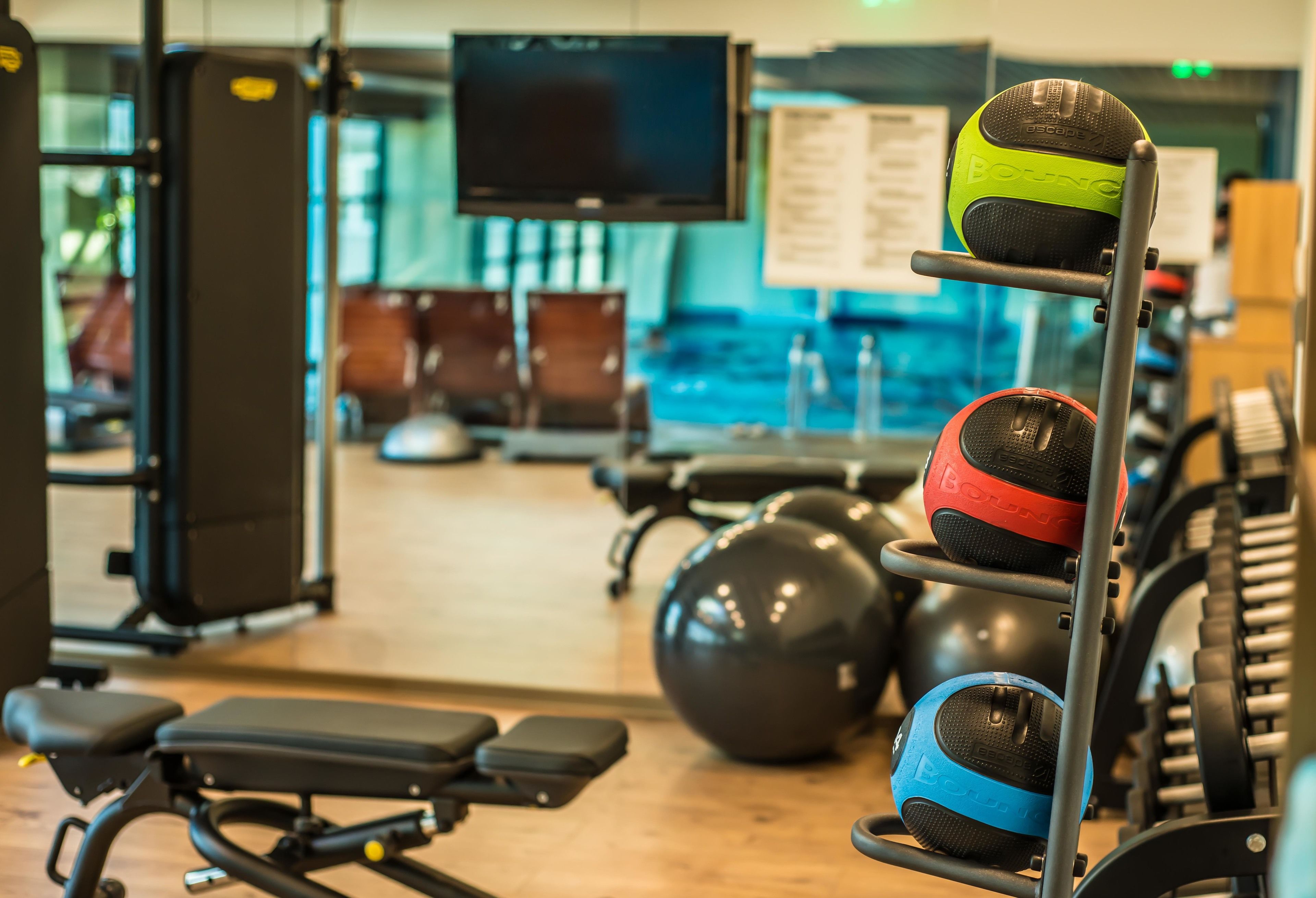 A gym with exercise equipment, a television, and a bulletin board.