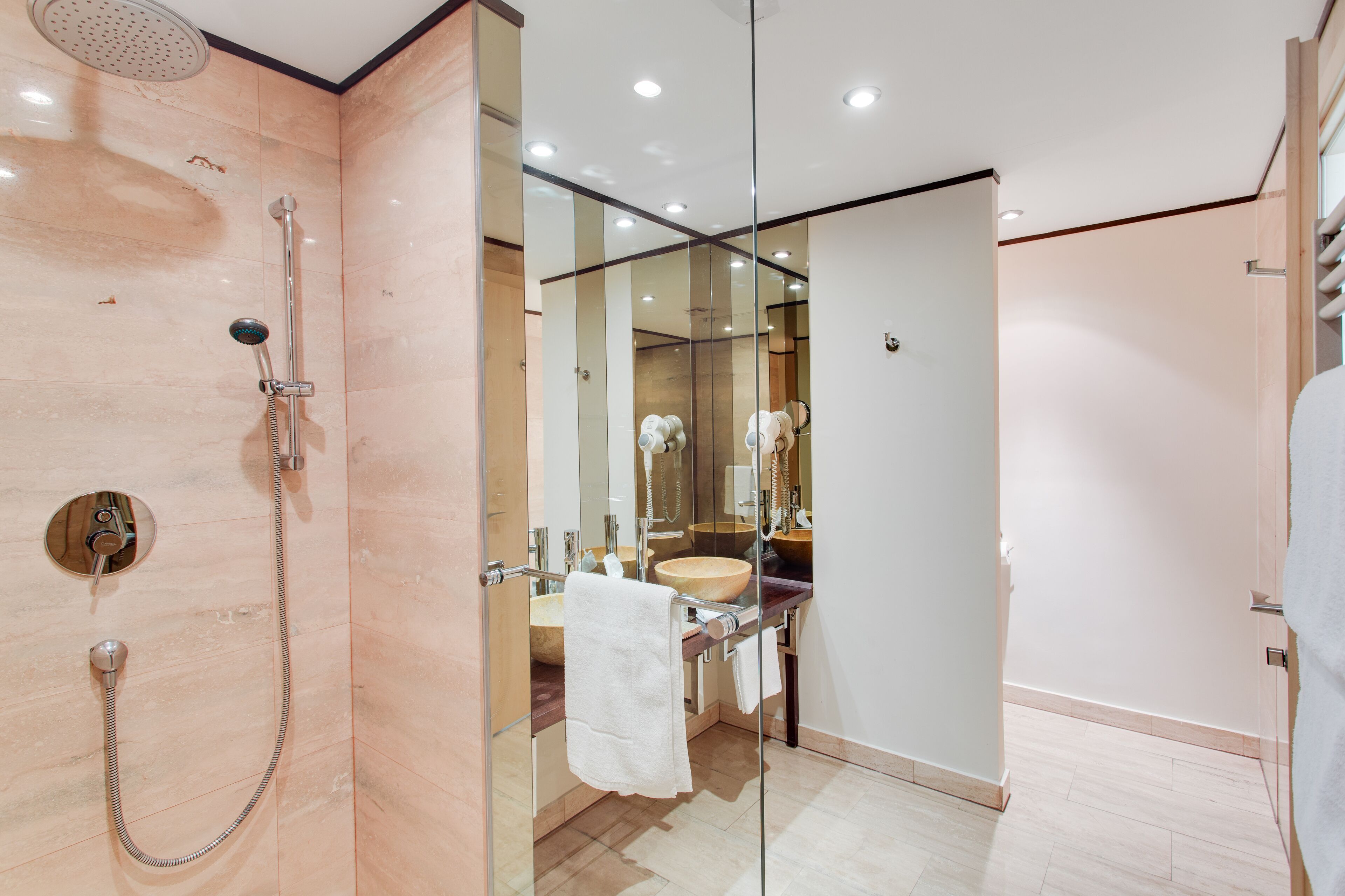 Un baño moderno con cabina de ducha de vidrio, tocador de madera y un espejo grande.