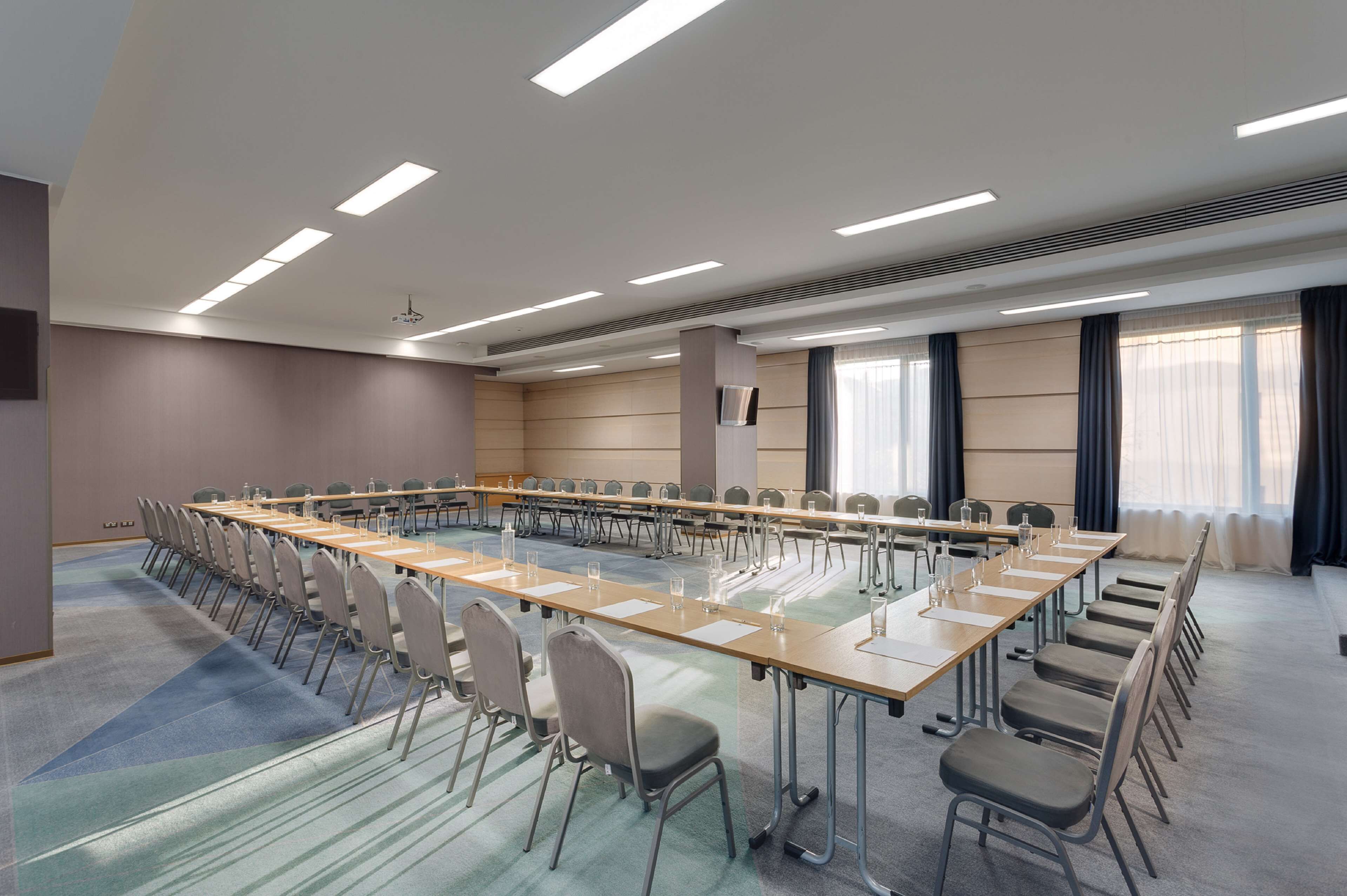 A conference room with a long table, chairs, and a projector screen.