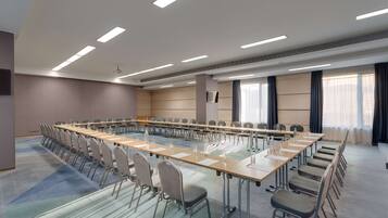 A conference room with a long table, chairs, and a projector screen.
