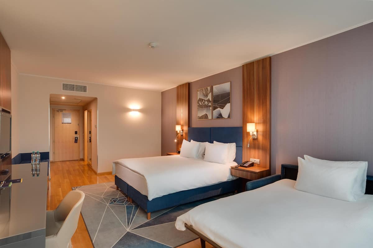Une chambre d’hôtel avec deux lits, un bureau, une chaise et une porte de salle de bain.