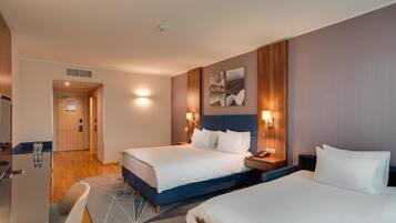 Une chambre d’hôtel avec deux lits, un bureau, une chaise et une porte de salle de bain.