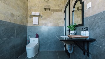 Casa de banho com sanita, lavatório, espelho e porta-toalhas.