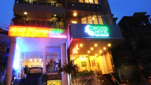 A multi-story hotel with illuminated signage for a massage center and an orchid hotel. - Orchid Hotel (Hue)