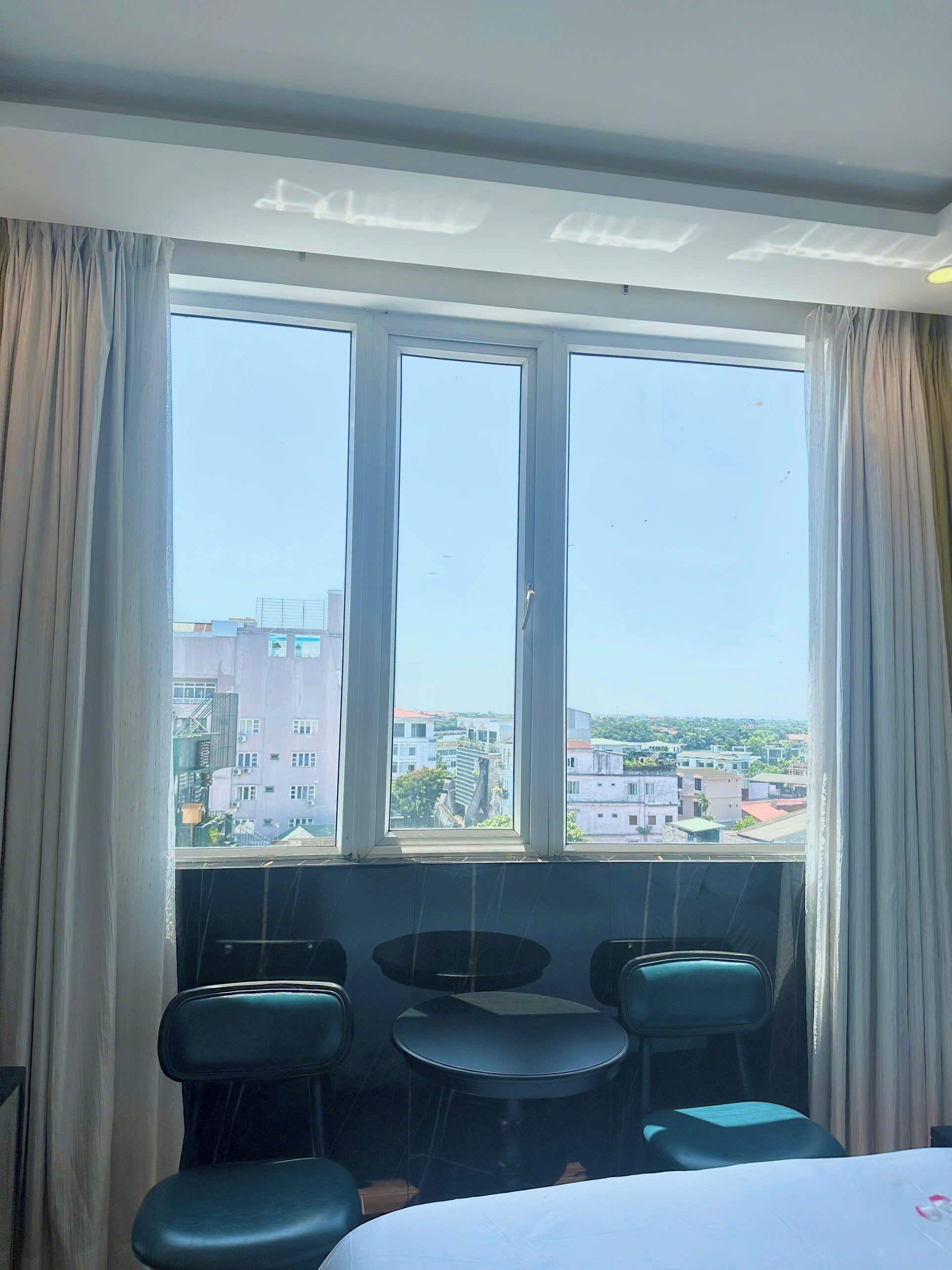 Una habitación de hotel con un ventanal grande, una cama y dos sillas.