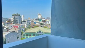 A balcony with a clear view of a cityscape, including buildings and a green-roofed structure. - Orchid Hotel (Hue)