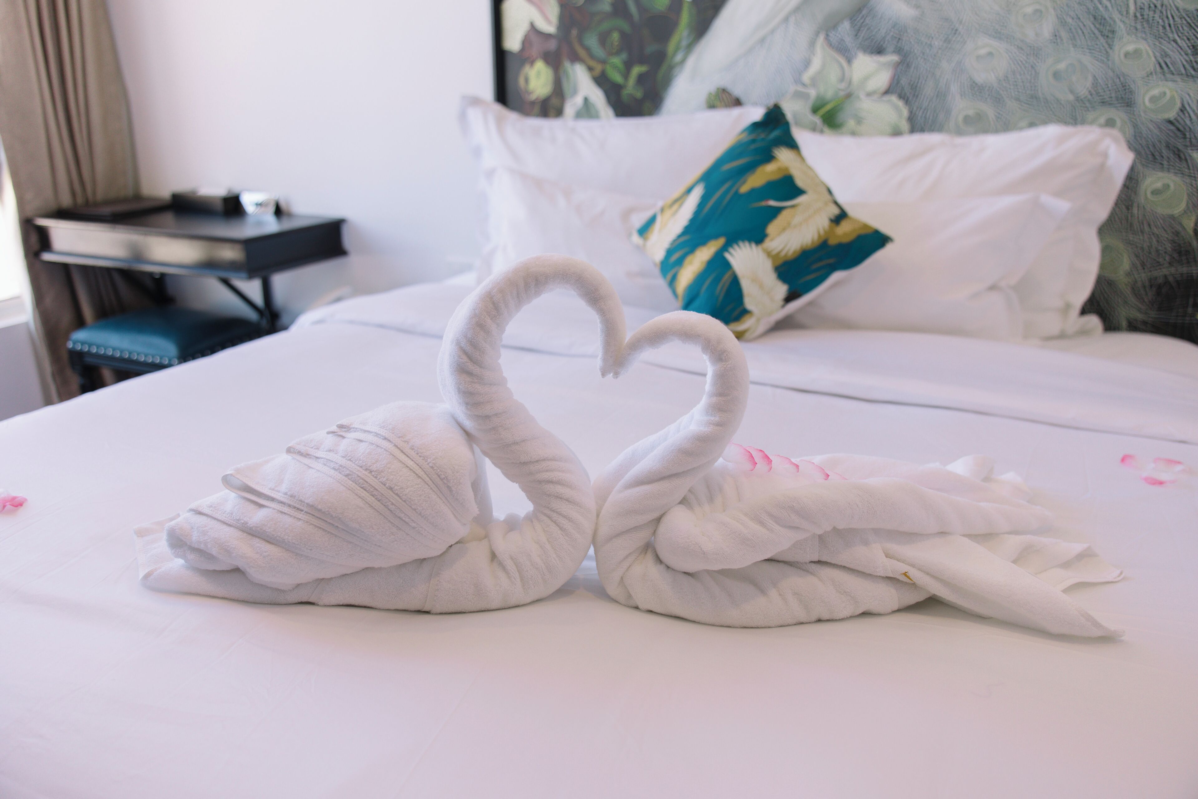 Un lit décoré avec des serviettes disposées en forme de cœur.