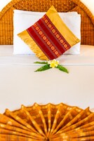A bed with a white mattress, a red and gold pillow, and a yellow and red decorative pillow.