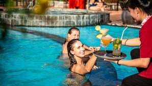 A poolside area with a hot tub, a bar area with drinks, and a person serving a drink. - White Sand Resort (Phan Thiet)