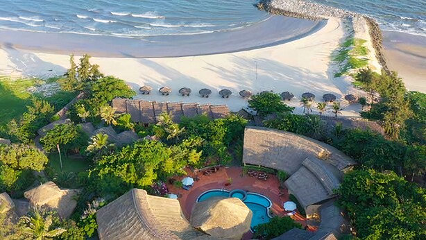 An aerial view of a resort with a beach, a pool area, and thatched-roof structures. - White Sand Resort (Phan Thiet)